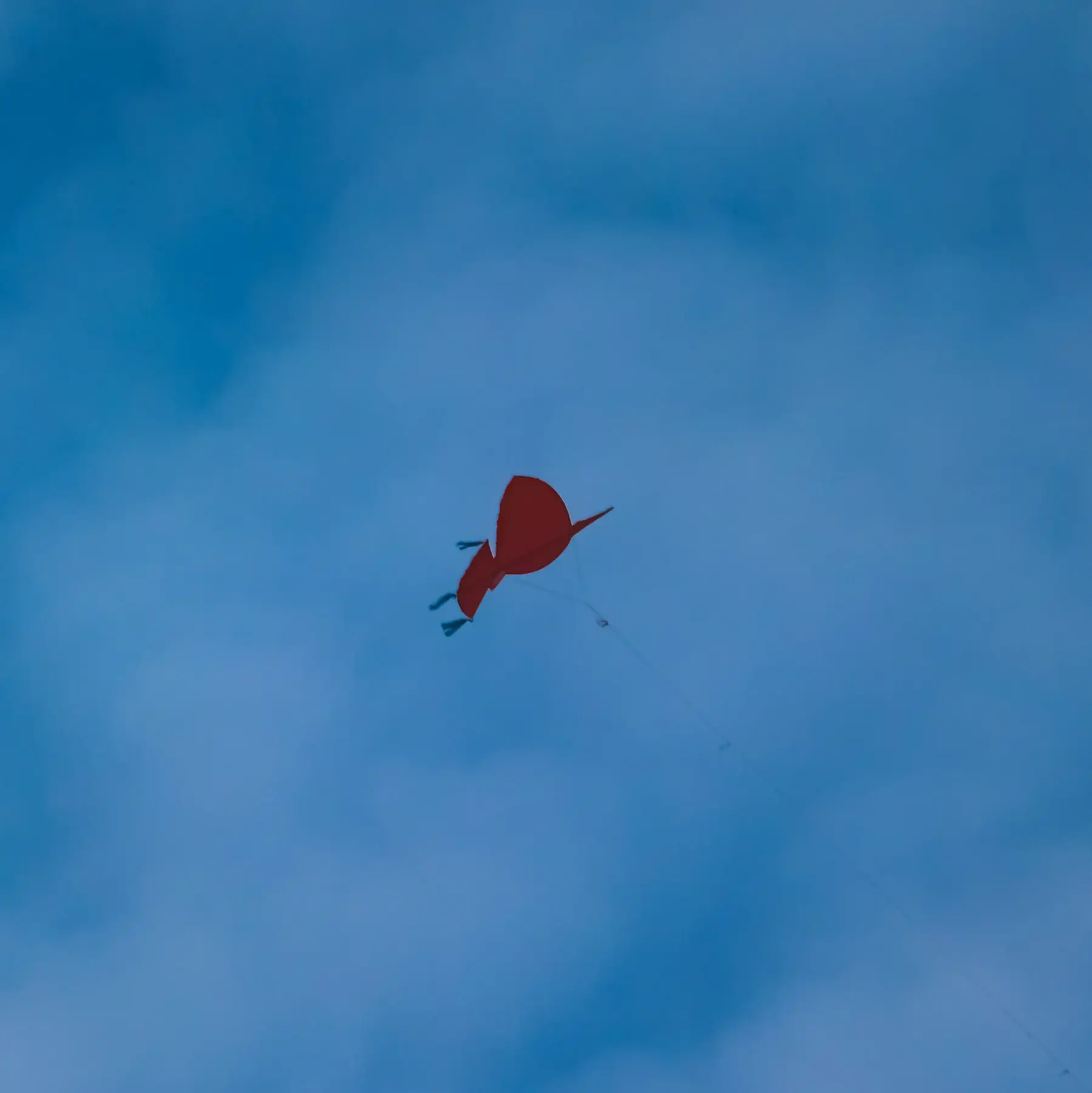 A red kite flying in a blue sky